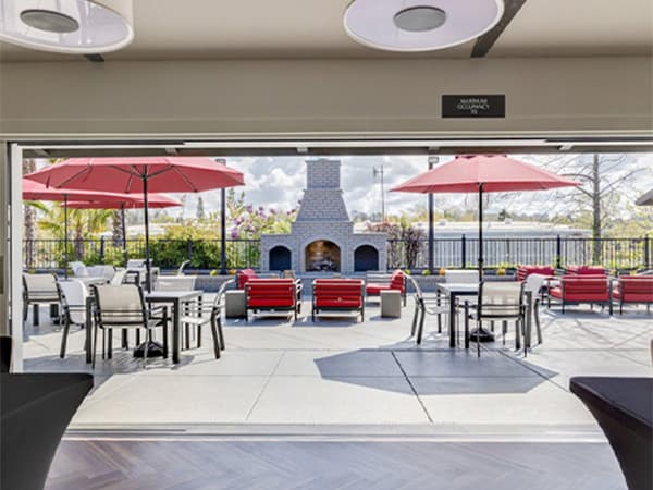 Outdoor HOA clubhouse patio by Jeff Smith Construction in Folsom. Outdoor area of an HOA clubhouse with tables, chairs, umbrellas, and a fireplace built by Jeff Smith Construction in Folsom, CA.